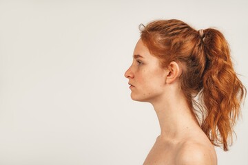 Close up face in profile natural redhead cute woman with freckles. Isolated over white background. Natural beauty and health