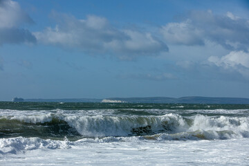 Fototapeta premium Stormy weather at the beach with crashing waves under a majestic blue sky