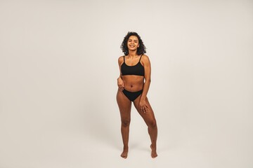 Photo of attractive black woman wears black underwear. Isolated over white background. Natural beauty and health