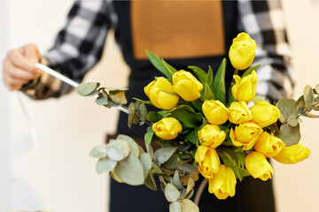 Florist makes a bouquet of fresh yellow tulips.