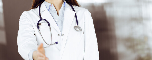 Unknown young woman doctor is offering helping hand for shaking hand or saving life. Medicine...