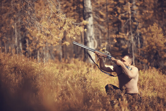hunting man / hunter with a gun hunting in the autumn forest, yellow trees landscape in the taiga