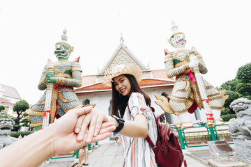 Tourist women leading man hand travel in temple of buddha statue