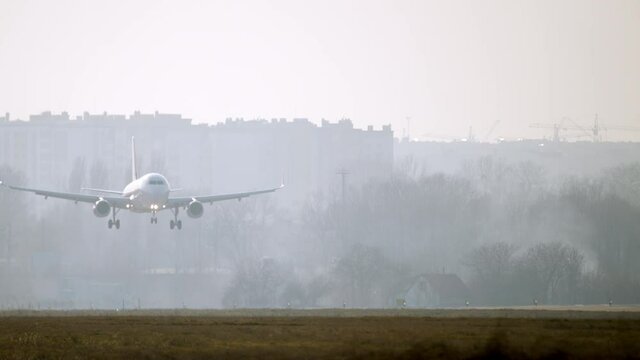 A passenger plane lands on the runway at the airport. The wheels of the airplane touch the runway and smoke appears from under them. Slow motion 4K video of the plane landing.