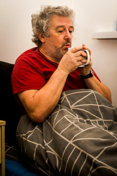 Senior man sitting in bed feeling unwell