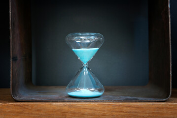 Blue sand running through a vintage glass hourglass