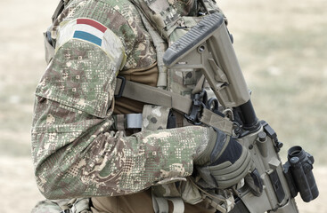 Soldier with assault rifle and flag of Luxembourg on military uniform. Collage.