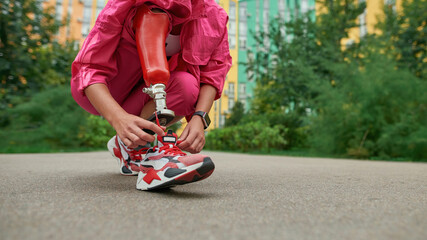 Disabled person with prosthetic leg tying shoelace