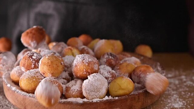 Baked castagnole with powdered sugar. Powder is poured onto baked goods. Traditional sweet pastries during the carnival period in italy. Round biscuits with sugar for the carnival of Venice. FullHD 