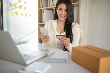 Portrait of young woman using credit card and  laptop for Online shopping	at home office