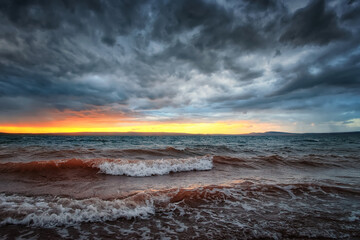 sunset light among dark rain clouds over a lake with waves from the wind Lake Bele in Khakassia