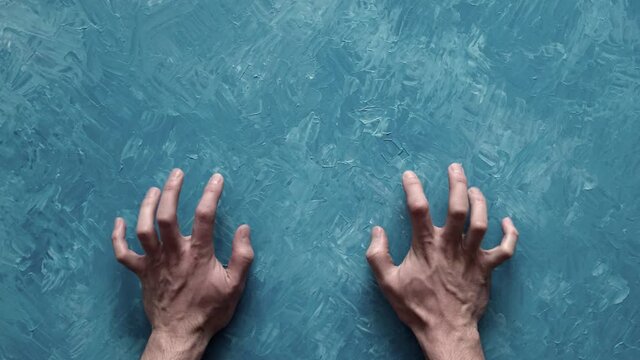 He scratches the wall with his hands. Two hands scrape their nails against the thick glass, trying to get inside the room