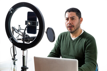 Male podcaster podcasting audio from his home studio by recording himself on his cell phone on...