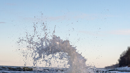 waves crashing against the backdrop of a blue sky