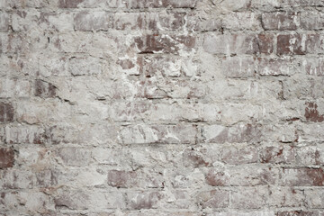 A brick wall with crumbling plaster from old age. The influence of wind and precipitation on materials in construction.