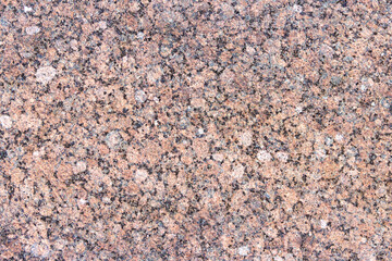 The texture of a hewn granite slab with a colorful pattern. Facing material for walls made of natural stone.