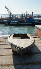 old wooden boat on concrete slabs in the background of a blue fishing boat