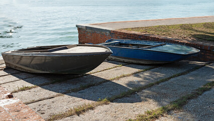 old wooden boats on the concrete embankment. Abandoned fishing boats 