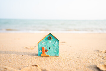 Fototapeta na wymiar Blue miniature model house on the beach and blue sky background, house construction ideas.