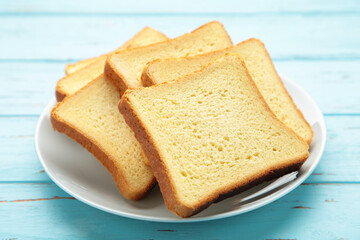 Pile of toasted bread slices on a single white plate on blue background.