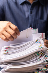 Vertical male office workers holding and writing documents on office desk, Stack of business overload paper.