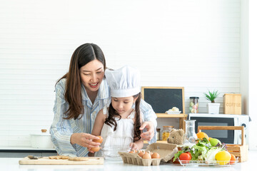 A young girl and daughter learned to cook breakfast with mom. A beautiful Asian woman was happy in the kitchen at home. 