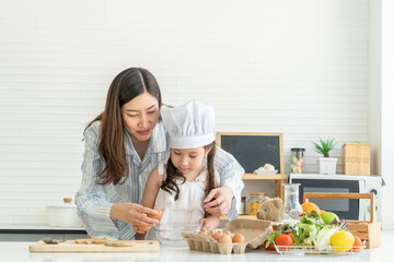 A young girl and daughter learned to cook breakfast with mom. A beautiful Asian woman was happy in the kitchen at home. 