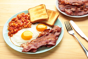 Traditional full English breakfast - fried eggs, beans, bacon and toast on brown background with copy space for text.