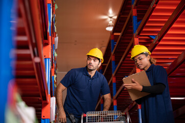 warehouse workers logistic team wearing hardhats to working in aisle between tall racks with packed...