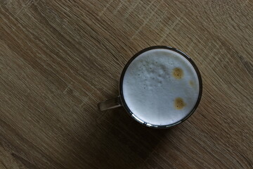 A cup with coffee on a wooden table in the room, made with a coffee machine