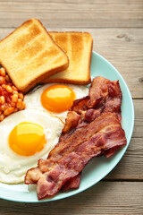 Traditional full English breakfast - fried eggs, beans, bacon and toast on grey wooden background. Vertical foto