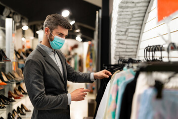 Man shopping for clothes wearing mask and social distancing