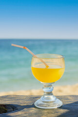 glass of orange juice on a sunny tropical beach with copy space