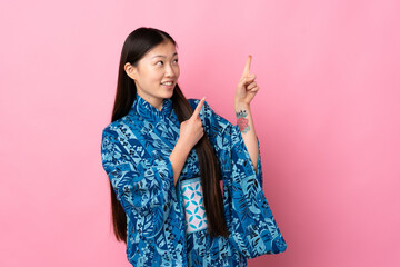 Young Chinese girl wearing kimono over isolated background pointing with the index finger a great idea