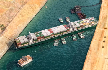 Foto op Canvas Ooit gegeven is vrijgelaten in het Suezkanaal. Inspanning om enorm ingeklemd containervrachtschip te laten drijven door sleepboten, baggerschip 3D-illustratie. Gigantisch vrachtschip verdreven en gelicht in Egyptisch Suezkanaal © Corona Borealis
