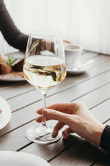 Girl holding glass of white wine in hand. Girls are having lunch at restaurant. Wine and dessert.