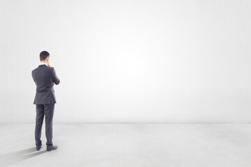 Thinking about future concept with businessman in empty room with blank light wall with copyspace...