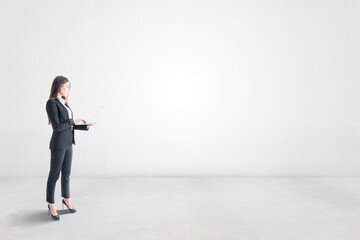 New idea and thinking about future concept with businesswoman with laptop in empty light room with blank wall. Mockup