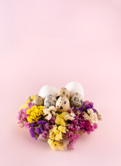 Minimal Easter decoration made of eggs and flowers. Pastel pink Holiday background.