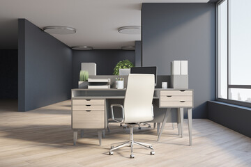 Stylish workplace from wooden furniture and light chair in sunny spacious office with grey walls and wooden parquet