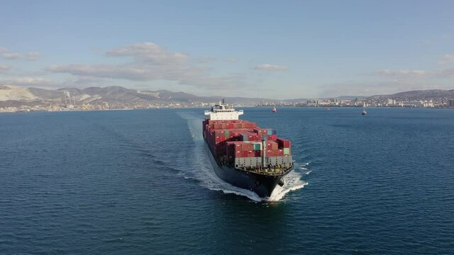 Ultra large loaded container ship cruising in open ocean, aerial view. High quality 4k drone footage of Cargo ship departing from the port. Concept of freight transportation, import export business