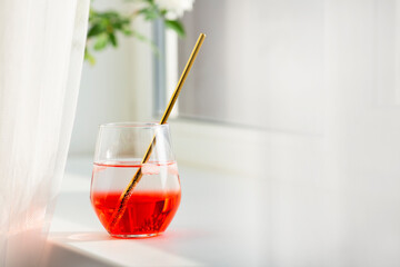 A refreshing cocktail in the summer is a great thirst quencher. Red grenadine and iced mineral water. Reusable metal tube in a glass.