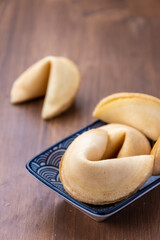 Top view of fortune cookies on Chinese plate, on wooden table, with selective focus, in vertical,...