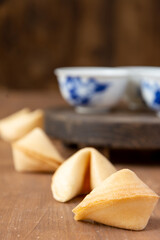 Close-up of fortune cookies and Chinese cups, on wooden table, with selective focus, vertical