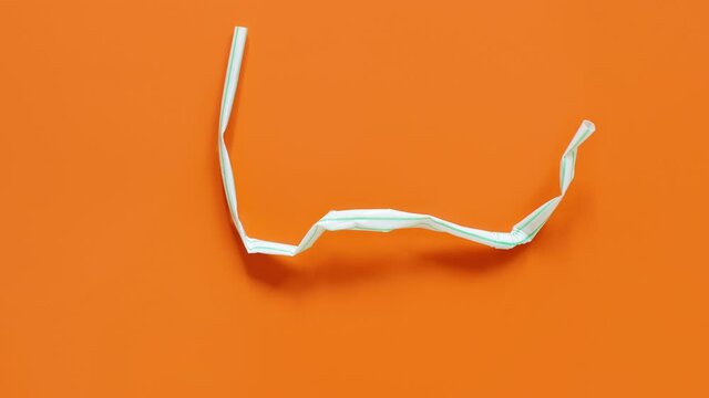 Used plastic drinking straws on the orange background top view