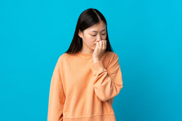 Young Chinese girl over isolated blue background having doubts