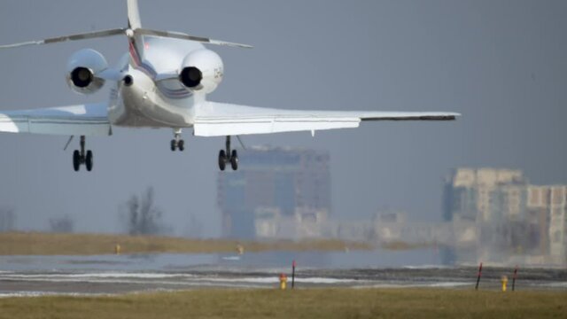 A small plane lands on the runway. Private plane lands at the airport against the backdrop of the city. Slow motion 4K video of an airplane.