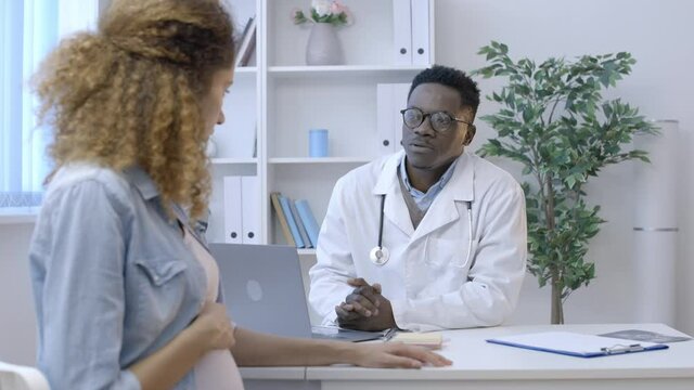 Clinic obstetrician talking to worried pregnant woman, bad news, diagnosis