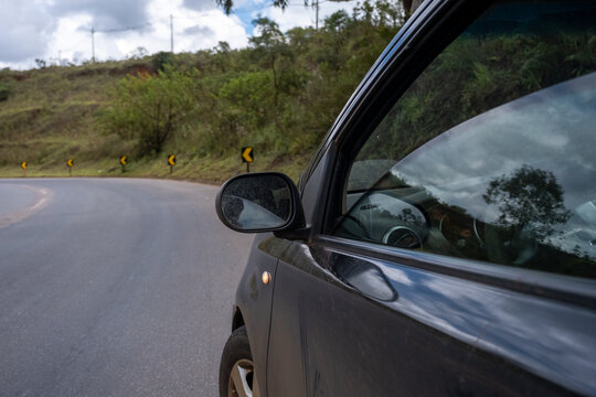 Carro preto parado a beira da estrada, com o vidro semiaberto, no interior de Minas Gerais