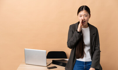 Chinese business woman in her workplace shouting with mouth wide open